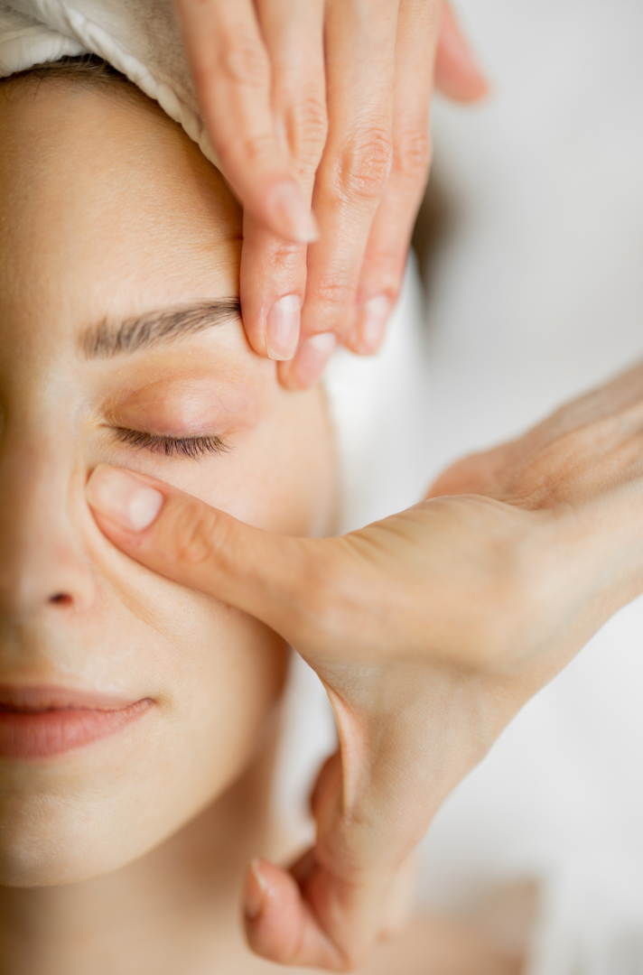 Close-up of a person receiving a facial massage with hands on a blurred background