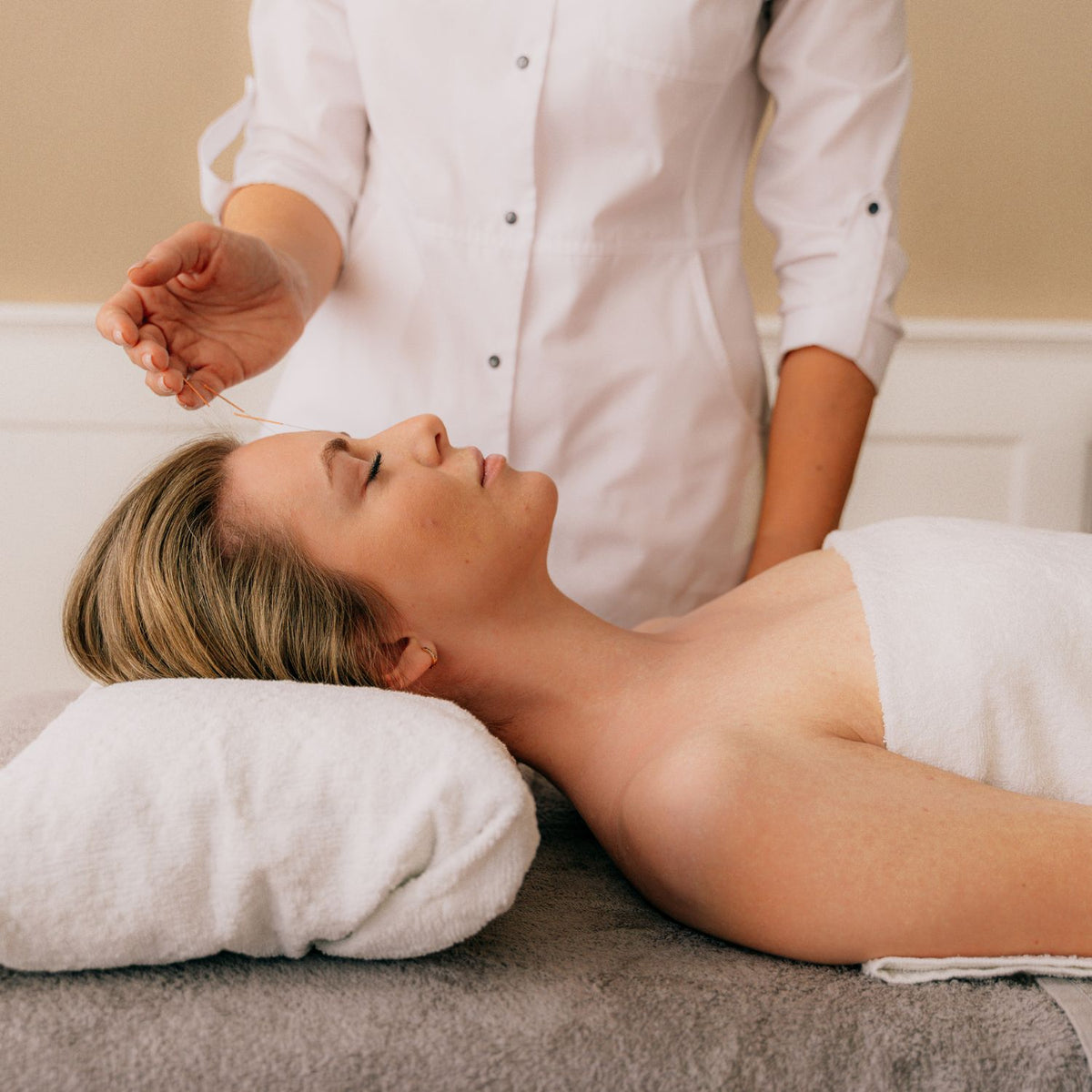Chinese medicine practitioner treating a client on a clinic treatment bed