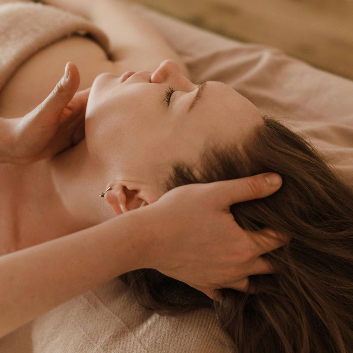 Hands cradling a client's head during a relaxing face and scalp massage