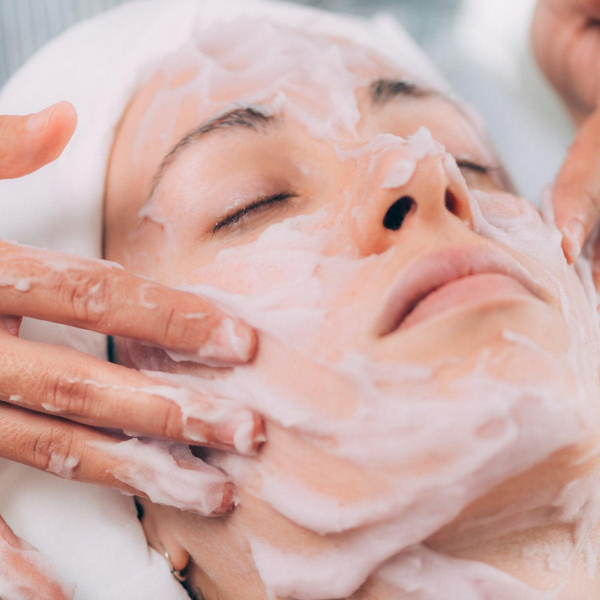 Herbal face mask being applied by hand during a facial treatment
