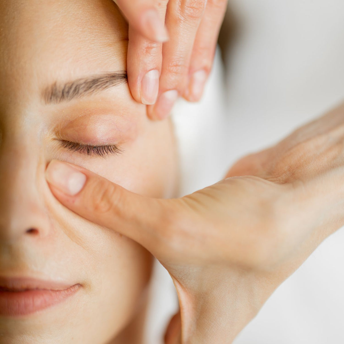 Close-up of lymphatic facial massage across the brow and cheek