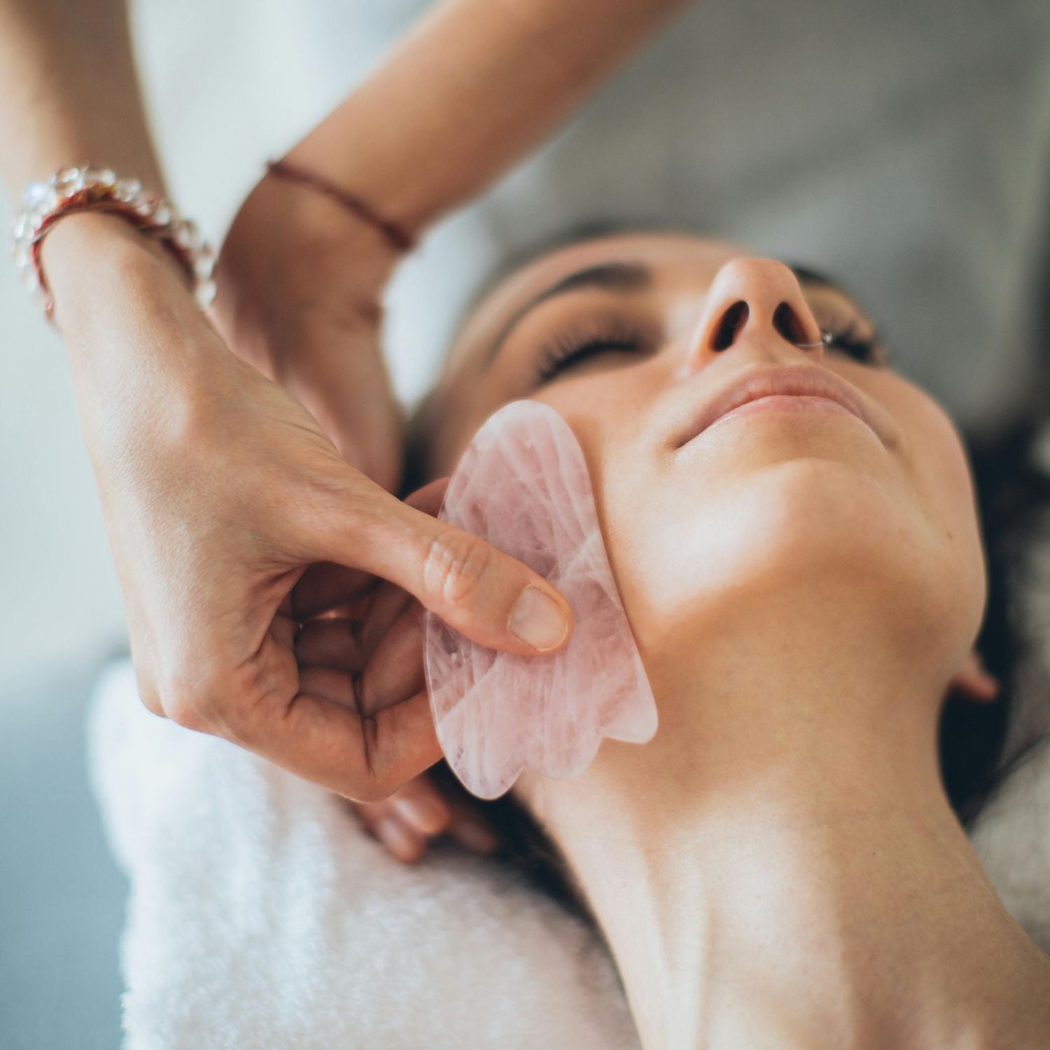 Rose quartz gua sha tool drawn along the neck and decolletage